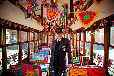 Tram Conductor standing aboard the Yarn Bomb Tram surrounded by crochet 